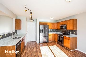 Noblesville house for rent - A kitchen with wooden cabinets and a black fridge.