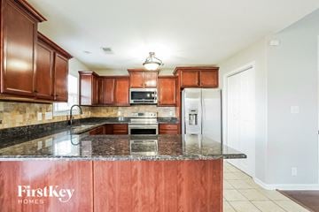 Clarksville house for rent - A kitchen with brown cabinets and a FirstKey Homes sign.
