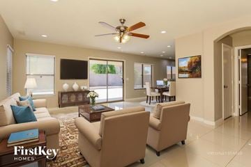 Glendale house for rent - A living room with a fan, two chairs, and a table with a vase of flowers on it.