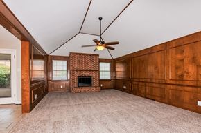 St Louis house for rent - an empty living room with a brick fireplace and a ceiling fan
