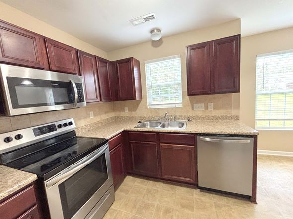 Hope Mills house for rent - A kitchen with brown cabinets and a black stove top oven.