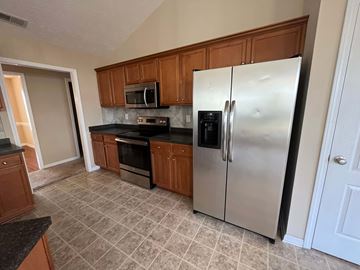 Hope Mills house for rent - a kitchen with stainless steel appliances and wooden cabinets