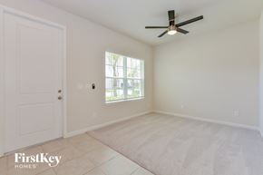 Sanford house for rent - A room with a ceiling fan and a window with a view of trees.
