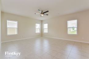 Sanford house for rent - A spacious room with a ceiling fan and three windows.