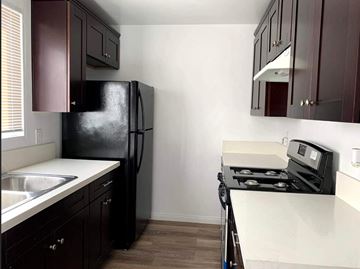 San Diego apartment for rent - A kitchen with a black fridge and stove top oven.