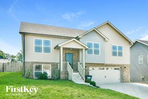 Clarksville house for rent - a beige house with a white garage door and a green lawn