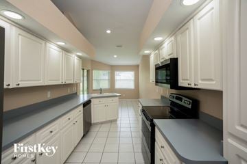 Clearwater house for rent - A kitchen with white cabinets and black appliances.