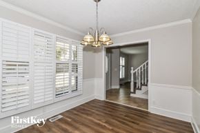 Olathe house for rent - a dining room with white plantation shutters and a chandelier