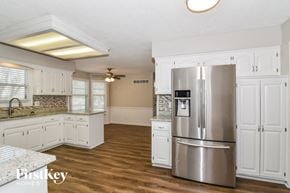 Olathe house for rent - a kitchen with white cabinets and a stainless steel refrigerator