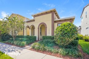 Winter Garden house for rent - a yellow house with a sidewalk and landscaping in front of it
