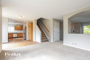 Aurora house for rent - an empty living room with a staircase and a kitchen