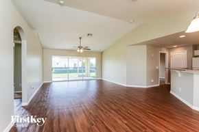 Lehigh Acres house for rent - A spacious room with wooden floors and a ceiling fan.