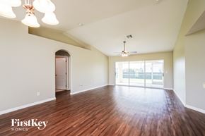 Lehigh Acres house for rent - A spacious room with wooden floors and a ceiling fan.