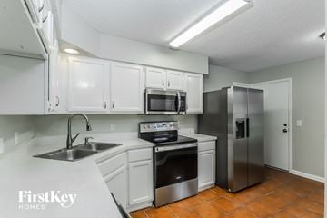 Jacksonville house for rent - a kitchen with white cabinets and stainless steel appliances