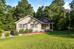 Dahlonega house for rent - A house with a well-kept lawn and trees in the background.