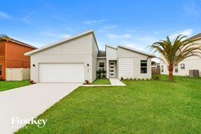 Poinciana house for rent - a white house with a lawn and a palm tree