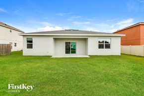 Poinciana house for rent - a small white house with a grassy yard in front of it