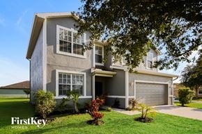 Lehigh Acres house for rent - A house with a garage and a tree in front of it.