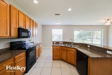Lehigh Acres house for rent - A kitchen with wooden cabinets and black appliances.