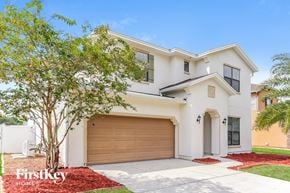 Jacksonville house for rent - A white two-story house with a garage door and a tree in front.