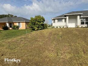 Cape Coral house for rent - A grassy area with two houses and a tree in the background.