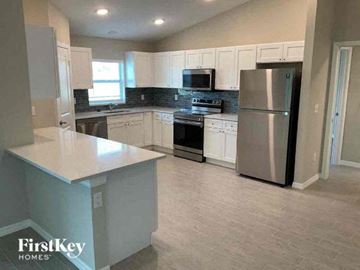 Cape Coral house for rent - A kitchen with a refrigerator, stove, and microwave.