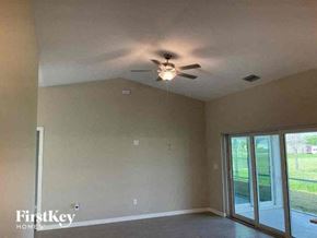 Cape Coral house for rent - A room with a ceiling fan and sliding glass doors.