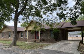 Monroe apartment for rent - A house with a red door is surrounded by trees.