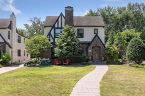 Minneapolis apartment for rent - A house with a white and black facade is surrounded by greenery.