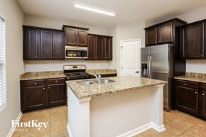 Dawsonville house for rent - a kitchen with granite counter tops and dark wood cabinets