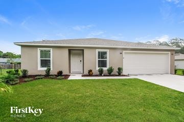 Palm Coast house for rent - a beige house with a lawn and a garage door