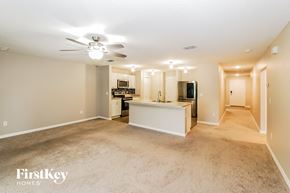 Palm Coast house for rent - an empty living room with a kitchen and a ceiling fan