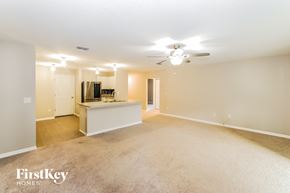 Palm Coast house for rent - an empty living room with a kitchen and a ceiling fan