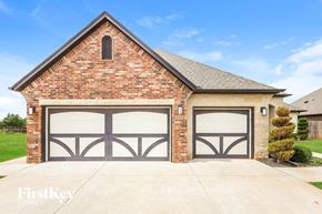 Mustang house for rent - a brick house with two garage doors on the side of it