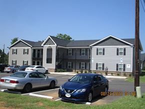Franklinton apartment for rent - A blue car is parked in front of a grey building.