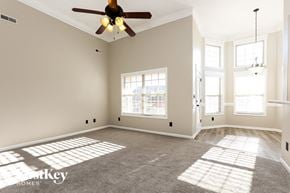 Clarksville house for rent - A spacious room with a ceiling fan and large windows.