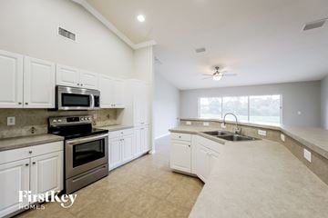 Lehigh Acres house for rent - a large kitchen with white cabinets and stainless steel appliances