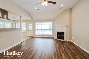 Humble house for rent - an empty living room with a fireplace and a ceiling fan