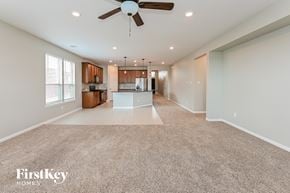 Katy house for rent - A spacious living room with a fan and a carpeted floor.