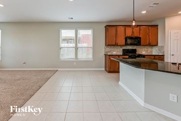 Katy house for rent - A kitchen with a black stove top oven and wooden cabinets.