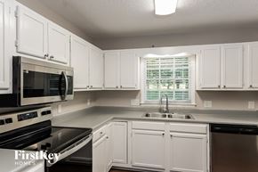 Trinity house for rent - a kitchen with white cabinets and a sink and a microwave