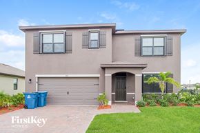 Palm Bay house for rent - a beige house with a garage door and a lawn