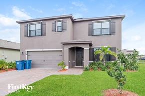 Palm Bay house for rent - a beige house with a garage and a lawn