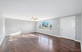 Romeoville house for rent - an empty living room with a ceiling fan and a window