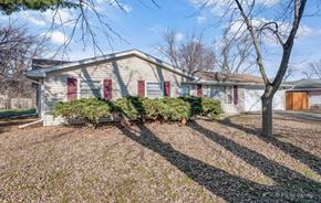 Romeoville house for rent - a small white house with red doors and a yard with trees