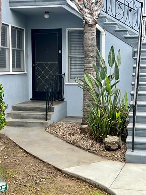 Long Beach apartment for rent - A house with a black door and a palm tree in front.