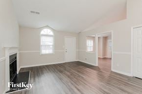 Charlotte house for rent - an empty living room with a fireplace and wood flooring