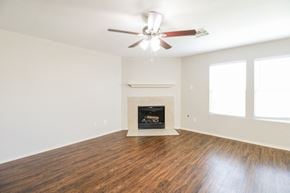 Cypress house for rent - an empty living room with a ceiling fan and a fireplace