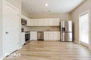 Jasper house for rent - a kitchen with white cabinets and a stainless steel refrigerator