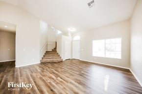 Surprise house for rent - A spacious room with wooden floors and a staircase leading to another room.
